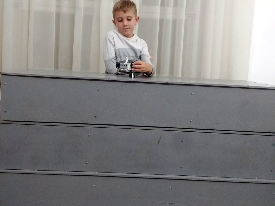 A child adjusting the wires on a small tabletop robot.