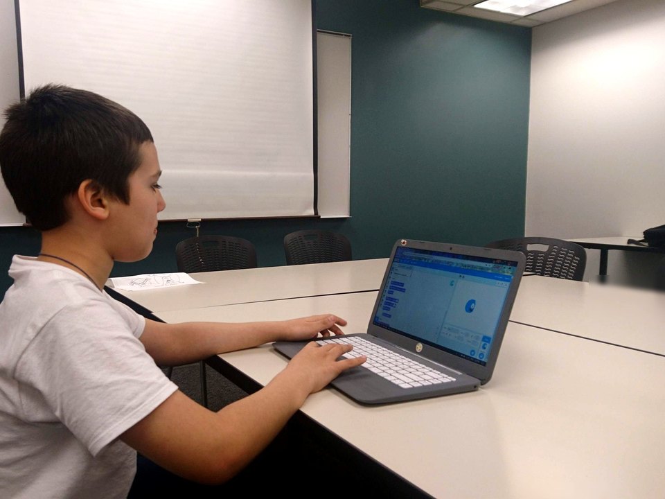 A child testing a Scratch project on a laptop.